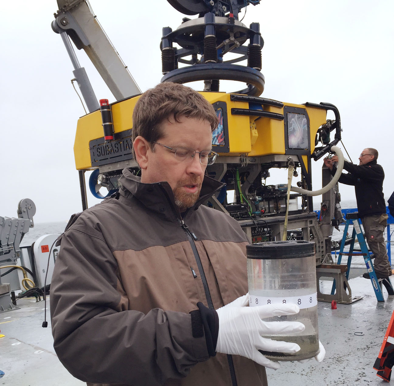 Dr. Marc Fries with a container of small particle samples collected by the ROV SuBastian.